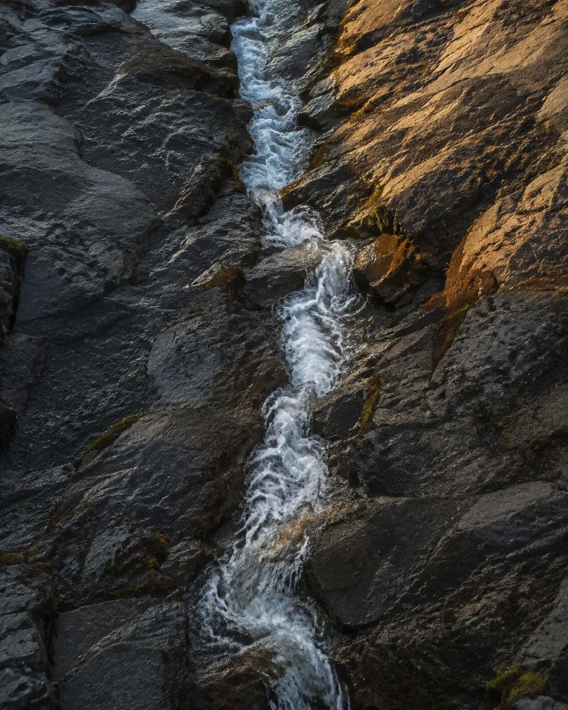 A mountain stream cutting a route through dark stone